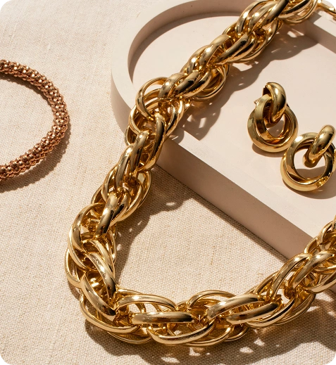 Close-up van een luxueuze gouden kettinghalsketting en bijpassende oorbellen tentoongesteld in warm natuurlijk licht op een premium neutrale achtergrond.