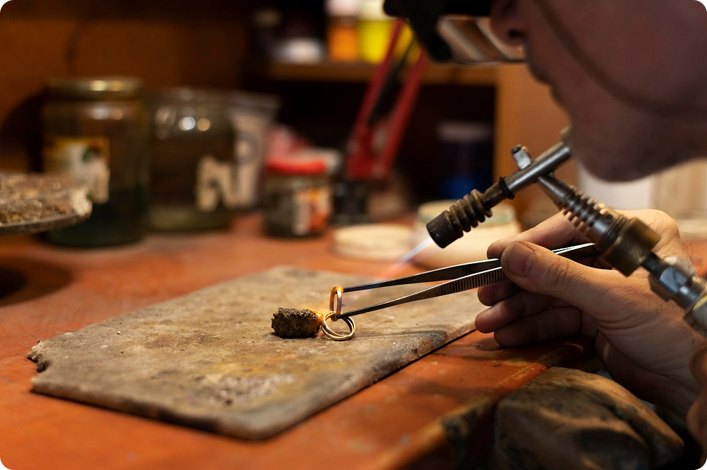 Close-up van een juwelier die een diamanten verlovingsring polijst met professionele tools, waarbij vakmanschap, precisie en luxe juwelencreatie worden benadrukt.
